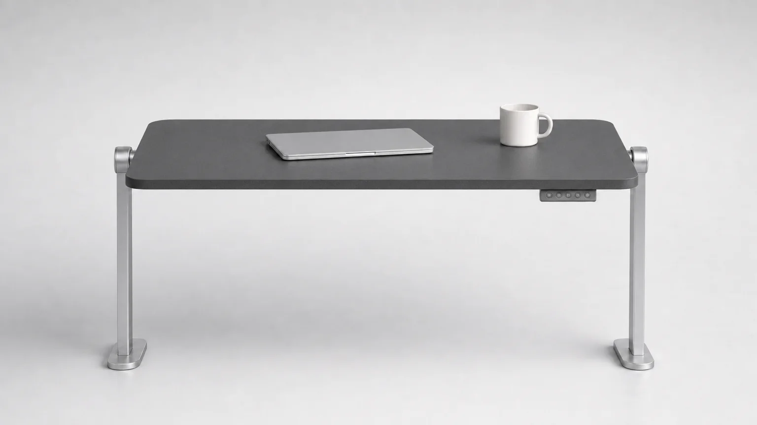 The same Versoflip One desk with the dark graphite laminate face upward, a laptop and a mug on the desktop